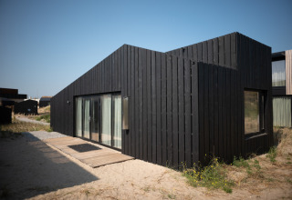 Moderna casa de playa negra en Sea Lodges Zandvoort 9, Países Bajos, rodeada de arena y dunas.