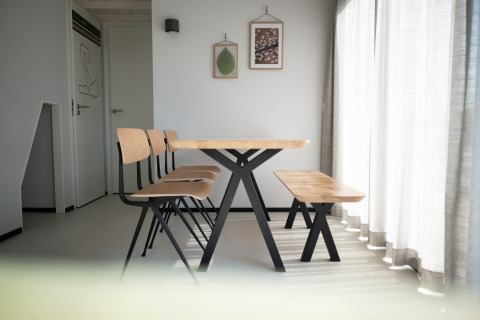 Comedor moderno en Sea Lodges Zandvoort 9, Países Bajos, con mesa y banco de madera junto a cortinas.