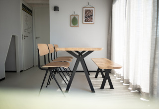 Comedor moderno en Sea Lodges Zandvoort 9, Países Bajos, con mesa y banco de madera junto a cortinas.