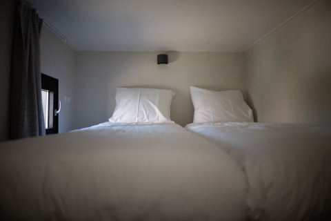 Twee eenpersoonsbedden met witte lakens in een knusse kamer van Sea Lodges Zandvoort 9, Nederland.