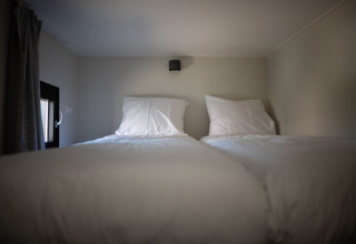 Dos camas individuales con sábanas blancas en un dormitorio acogedor de Sea Lodges Zandvoort 9 en Países Bajos.