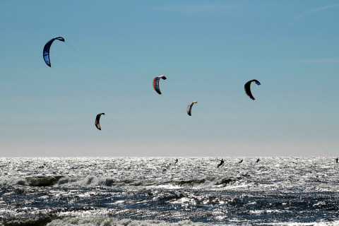 Kitesurfistas disfrutan del mar brillante frente a Sea Lodges Zandvoort 9 en Países Bajos bajo un cielo azul claro.