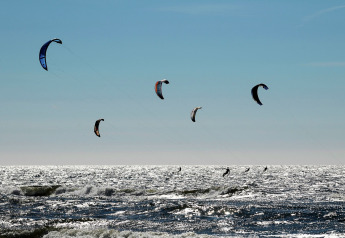 Kitesurfer gleiten ĂĽber das glitzernde Wasser bei Sea Lodges Zandvoort 9 in den Niederlanden an einem klaren Tag.