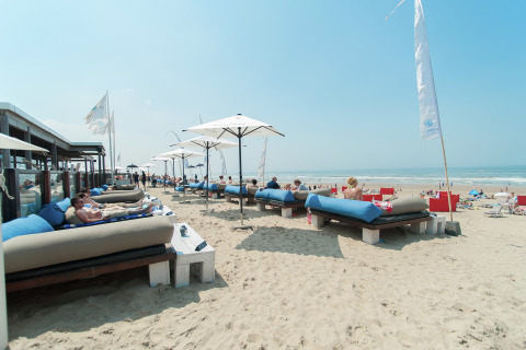 Personas descansan en camas con sombrillas en la playa de Sea Lodges Zandvoort 9, Países Bajos.
