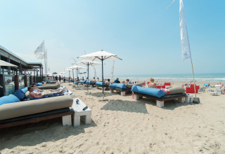 Personas descansan en camas con sombrillas en la playa de Sea Lodges Zandvoort 9, Países Bajos.