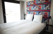 Schlafzimmer im Sea Lodges Zandvoort 9, Niederlande, mit zwei Einzelbetten und auffälliger Posterwand.