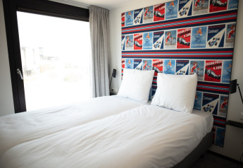 Schlafzimmer im Sea Lodges Zandvoort 9, Niederlande, mit zwei Einzelbetten und auffälliger Posterwand.