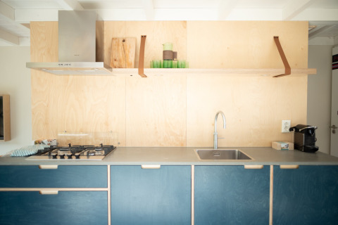 Cocina moderna con armarios azules, pared de madera, estufa de gas y fregadero en Sea Lodges Zandvoort 9.