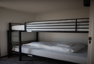 Literas con estructura negra y sábanas blancas en una habitación de Sea Lodges Zandvoort 9, Países Bajos.