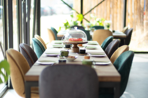 Tasteful dining setup with colorful chairs by large windows at Sea Lodges «Zandvoort 11» in the Netherlands.