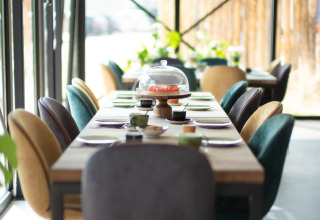 Tasteful dining setup with colorful chairs by large windows at Sea Lodges «Zandvoort 11» in the Netherlands.