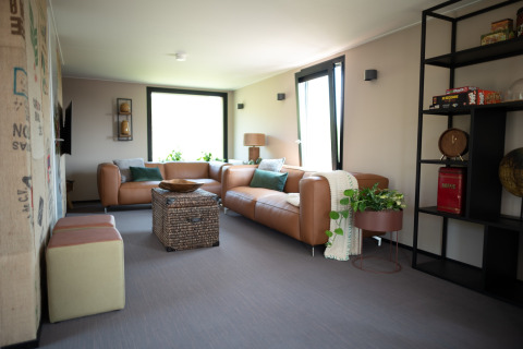 Modern living room at Sea Lodges Zandvoort 11 featuring leather sofas, large windows, and cozy decor.