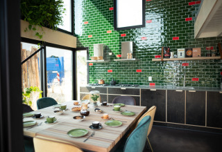 Modern kitchen and dining area with green tiles at Sea Lodges Zandvoort 11 beach house, Netherlands.