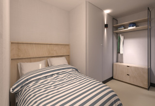 A modern bedroom with a single bed, striped bedding, and open wardrobe at Sea Lodges Zandvoort 11, Netherlands.