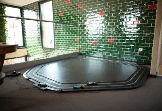 Toy race track on the floor in a modern room with green tile walls at Sea Lodges Zandvoort 11, Netherlands.