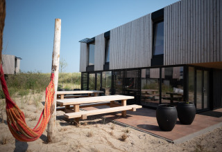 Outdoor terrace at Sea Lodges Zandvoort 11 in the Netherlands, with picnic benches and hammock in sand.