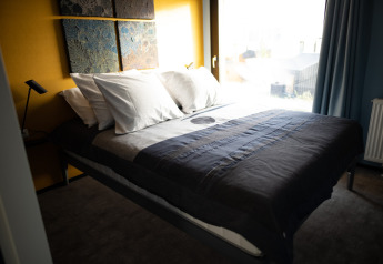 Slaapkamer met dubbel bed, vier kussens en natuurlijk licht bij Sea Lodges Zandvoort 6, Nederland.