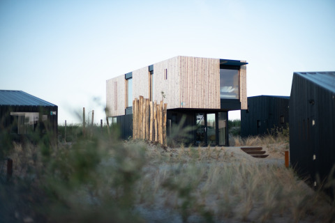 Modern strandhuis Sea Lodges ‘Zandvoort 6’ in Nederland, omringd door duinen en grassen.