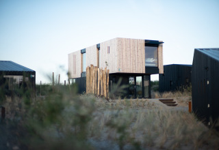 Modern strandhuis Sea Lodges ‘Zandvoort 6’ in Nederland, omringd door duinen en grassen.