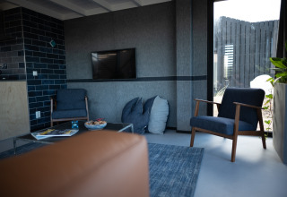 Moderne zithoek in Sea Lodges Zandvoort 6, Nederland, met blauwe zetels en grote ramen.