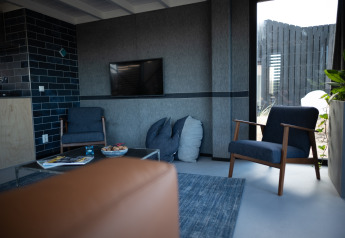 Moderne zithoek in Sea Lodges Zandvoort 6, Nederland, met blauwe zetels en grote ramen.