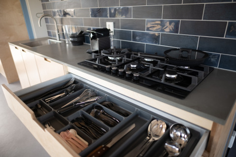 Moderne keukentablet met open besteklade, gasvuur en blauwe tegels in Sea Lodges Zandvoort.