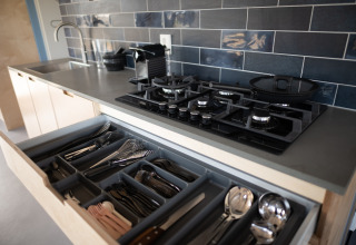 Moderne keukentablet met open besteklade, gasvuur en blauwe tegels in Sea Lodges Zandvoort.