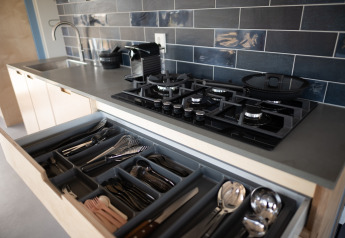 Moderne keukentablet met open besteklade, gasvuur en blauwe tegels in Sea Lodges Zandvoort.