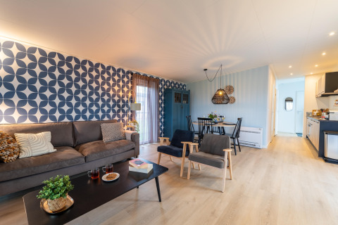 Bright, modern living and dining space at «By the Baker» lodge in the Netherlands with geometric wallpaper.