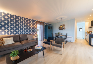 Bright, modern living and dining space at «By the Baker» lodge in the Netherlands with geometric wallpaper.
