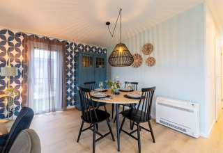 Modern dining area with black table, chairs, patterned wallpaper, and blue cabinet at 'By the Baker', Netherlands.