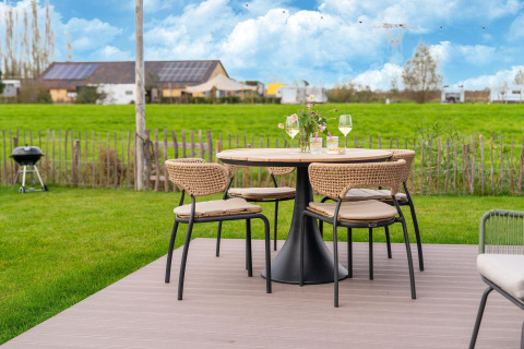 Gartentisch mit vier Stühlen, Wein und Blumen in ländlicher Kulisse bei By the Baker in den Niederlanden.