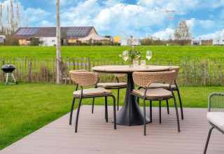Gartentisch mit vier Stühlen, Wein und Blumen in ländlicher Kulisse bei By the Baker in den Niederlanden.
