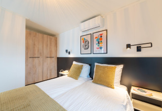 Modernes Schlafzimmer im 'By the Baker'-Lodge in den Niederlanden mit Doppelbett, Schrank und Kunst.