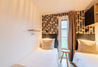 Contemporary lodge room with two single beds, patterned wallpaper, small window and simple furnishings.