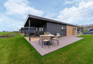 Moderne Ferienlodge ‘By the Baker’ in den Niederlanden mit Terrasse, Möbeln und gepflegtem grünen Rasen.