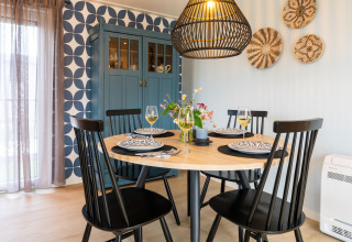 Dining area at 'By the Baker' lodge in the Netherlands with round table, black chairs and modern decor.