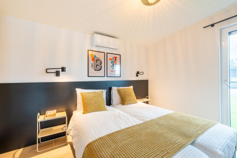 Modernes Schlafzimmer in der Lodge By the Baker in den Niederlanden mit zwei Einzelbetten und gelber Deko.