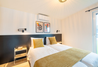 Modernes Schlafzimmer in der Lodge By the Baker in den Niederlanden mit zwei Einzelbetten und gelber Deko.