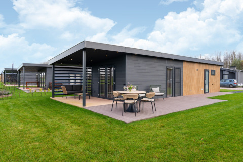 Moderne Lodge „By the Baker“ in den Niederlanden mit Holzterrasse und stilvollen Gartenmöbeln.