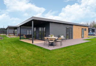 Moderne Lodge „By the Baker“ in den Niederlanden mit Holzterrasse und stilvollen Gartenmöbeln.