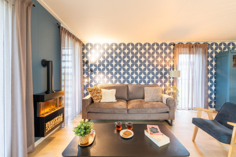 Helles Wohnzimmer der 'By the Baker'-Lodge in den Niederlanden mit moderner Couch und stilvoller Deko.