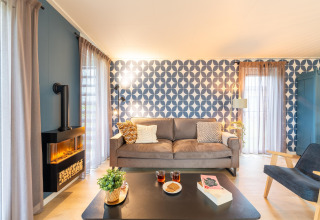 Helles Wohnzimmer der 'By the Baker'-Lodge in den Niederlanden mit moderner Couch und stilvoller Deko.