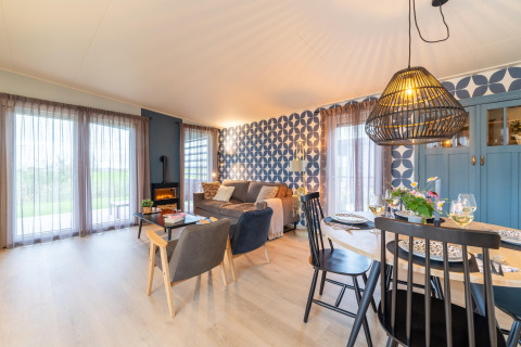 Bright, stylish living and dining area at ‘By the Baker’ lodge in the Netherlands, featuring patterned wallpaper.