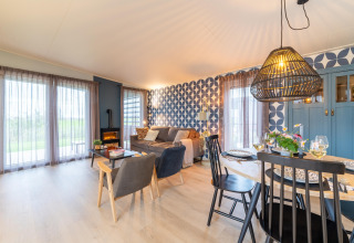 Bright, stylish living and dining area at ‘By the Baker’ lodge in the Netherlands, featuring patterned wallpaper.