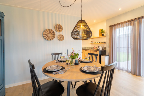Essbereich in der Lodge 'By the Baker' in den Niederlanden mit modernem Interieur und gedecktem Tisch.