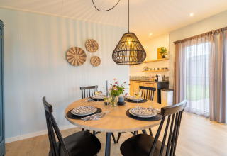 Dining area at 'By the Baker' lodge in the Netherlands, featuring modern décor, set table, and pendant lamp.