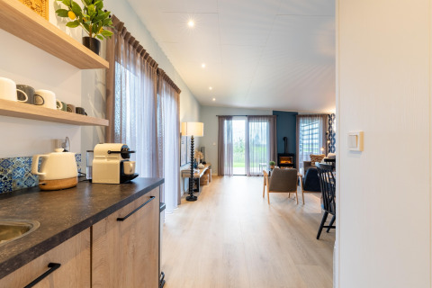 Helles Innenraumfoto von Wohnzimmer und Küchenzeile in der Lodge „By the Baker“ in den Niederlanden.