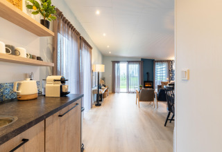 Bright interior photo of living room and kitchenette at lodge 'By the Baker' in the Netherlands.