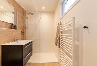 Modernes, minimalistisches Badezimmer mit Dusche, Waschbecken und Handtuchheizkörper in der Lodge 'By the Baker', Niederlande.
